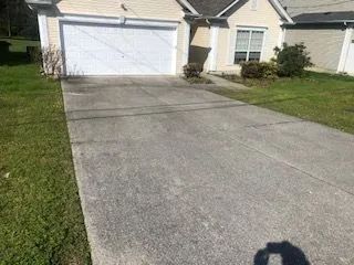 A concrete driveway leading to a house with a white garage door.