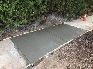 A concrete walkway is being built next to a bush.