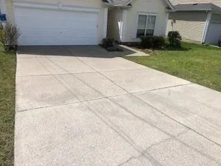 A concrete driveway leading to a house with a white garage door.