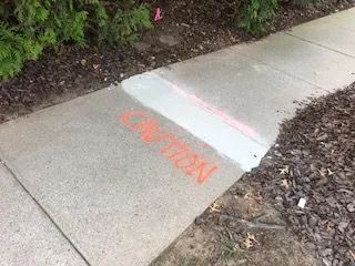 A sidewalk with the word caution painted on it.