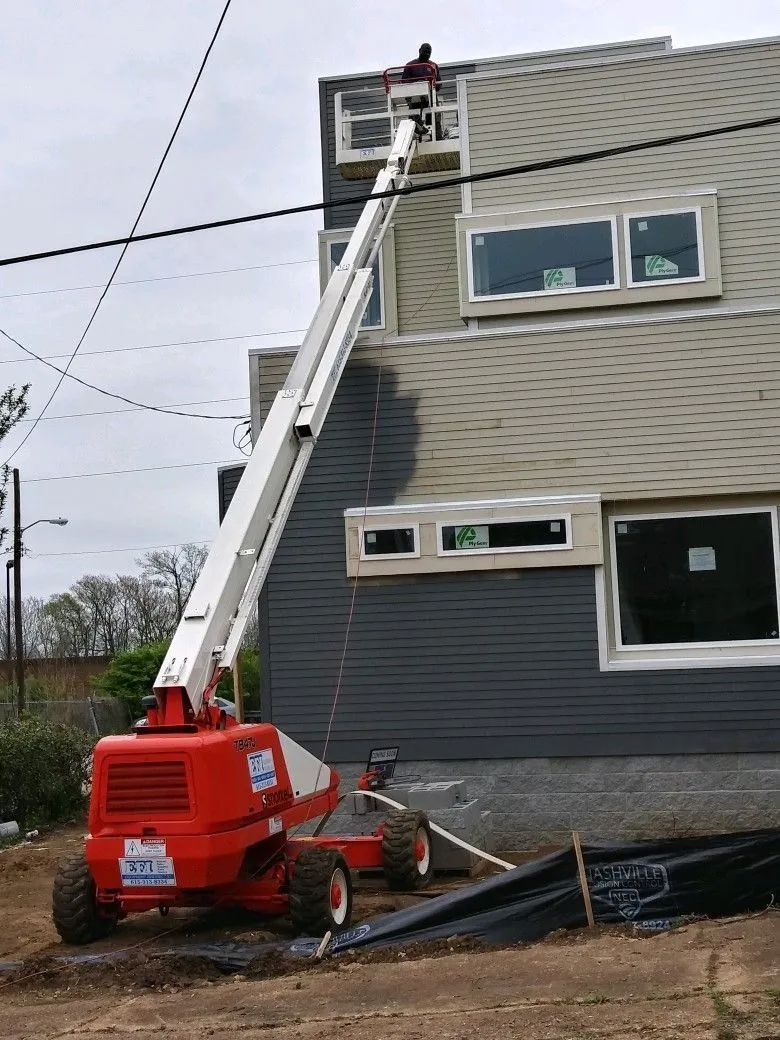 A crane is being used to paint the side of a building.