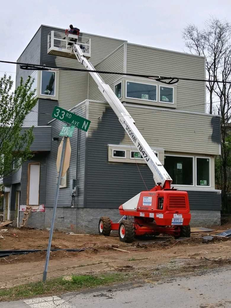 A red and white crane is sitting in front of a house under construction.