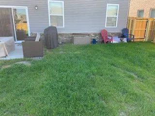 A backyard with a lot of grass and a house in the background.
