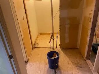 A blue bucket is sitting on the floor in a room.