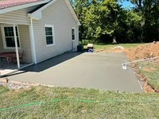 A concrete patio is being built in front of a house.