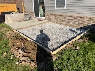 A concrete patio is being built in front of a house.