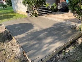A concrete walkway is being built in front of a house.
