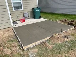 A concrete patio is being built in front of a house.
