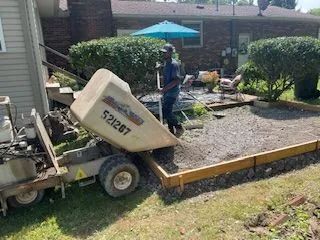 A man is working on a concrete driveway in front of a house.