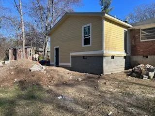 A small yellow house is being built next to a brick house.