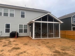 There is a screened in porch in the backyard of a house.