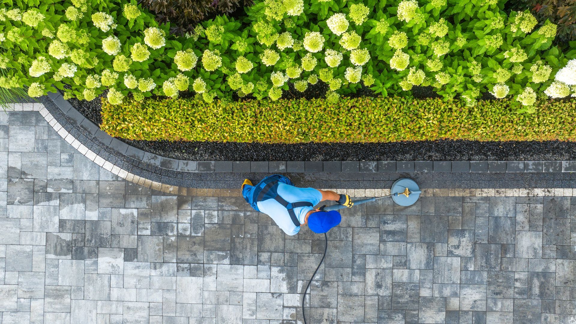 An aerial view of a person cleaning a patio with a broom.