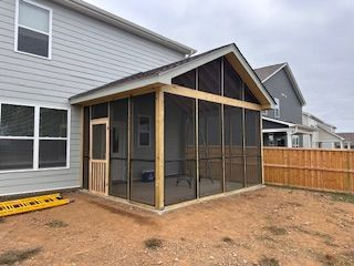A screened in porch is being built in the backyard of a house.