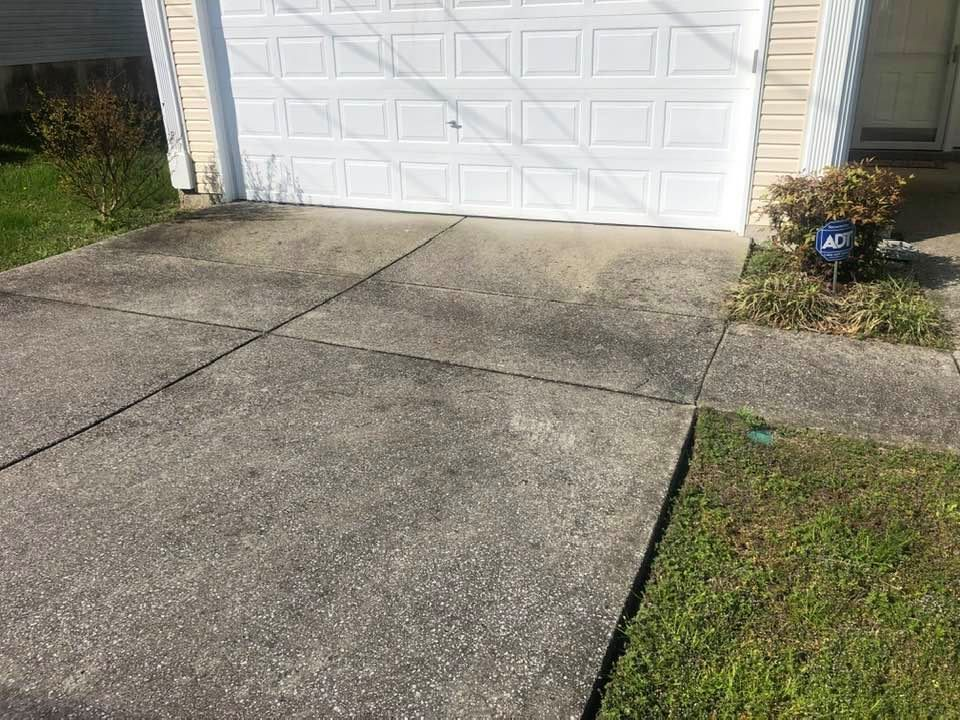 A dirty concrete driveway in front of a garage door.