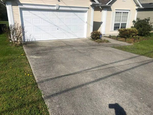A concrete driveway in front of a house with a garage door.