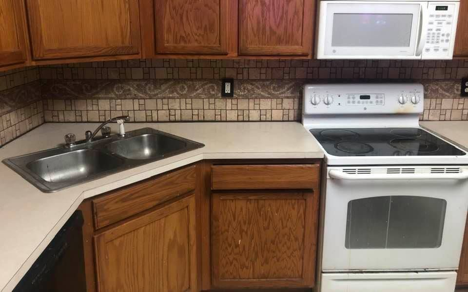 A kitchen with a stove , sink , and microwave.