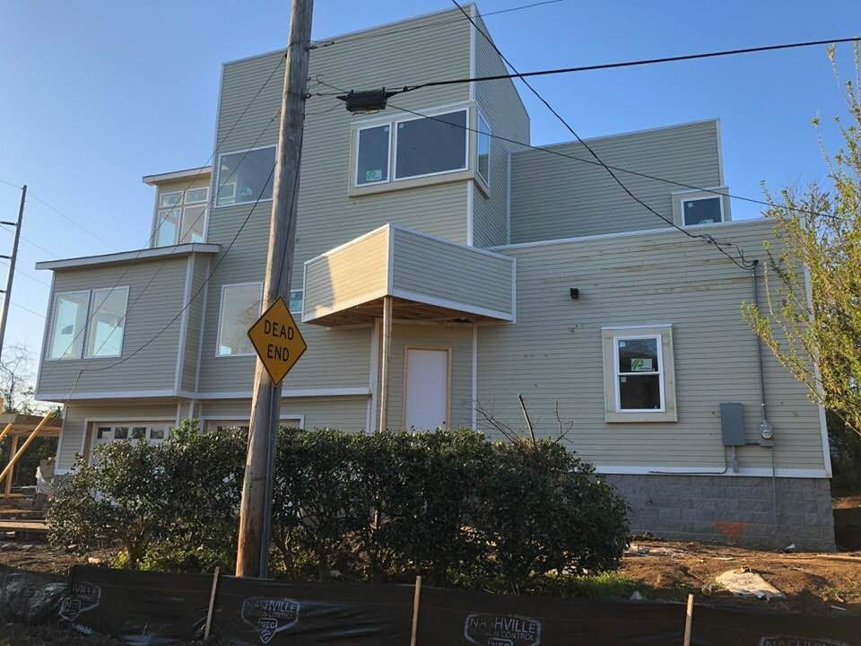 A yellow sign on a pole in front of a large house