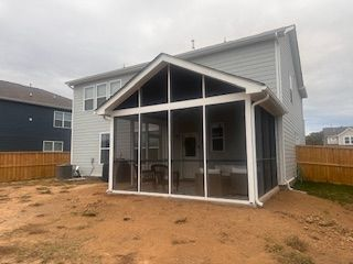 There is a screened in porch in the backyard of a house.