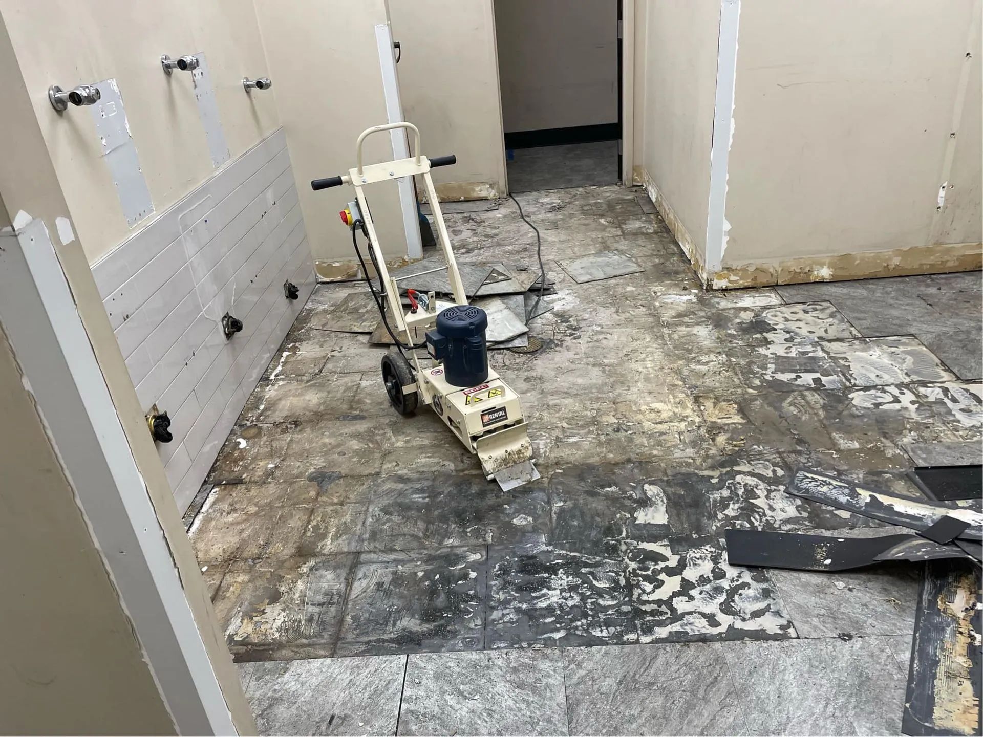 A machine is sitting on the floor of a bathroom.