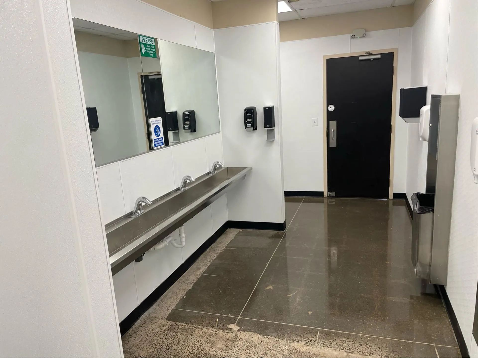 A hallway with a sink and a mirror in a bathroom.