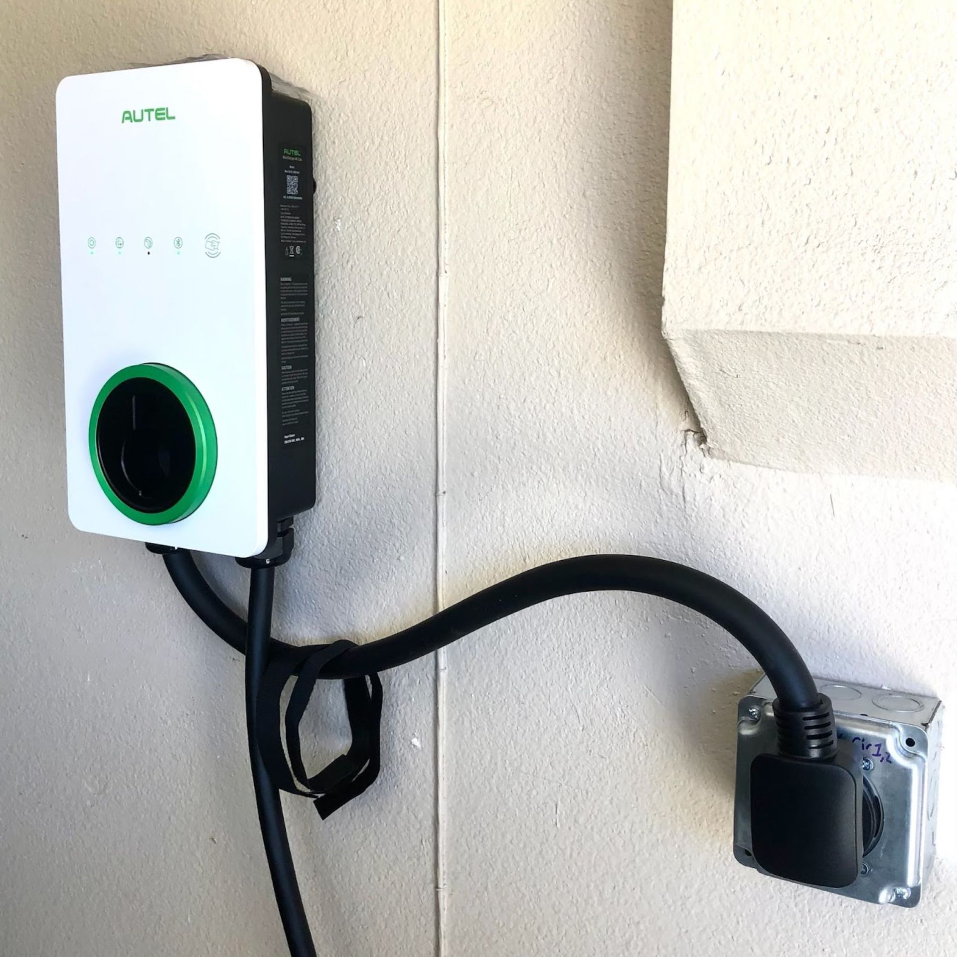 White Autel EV charger mounted on a wall, black cable connects to a 14-50 outlet.
