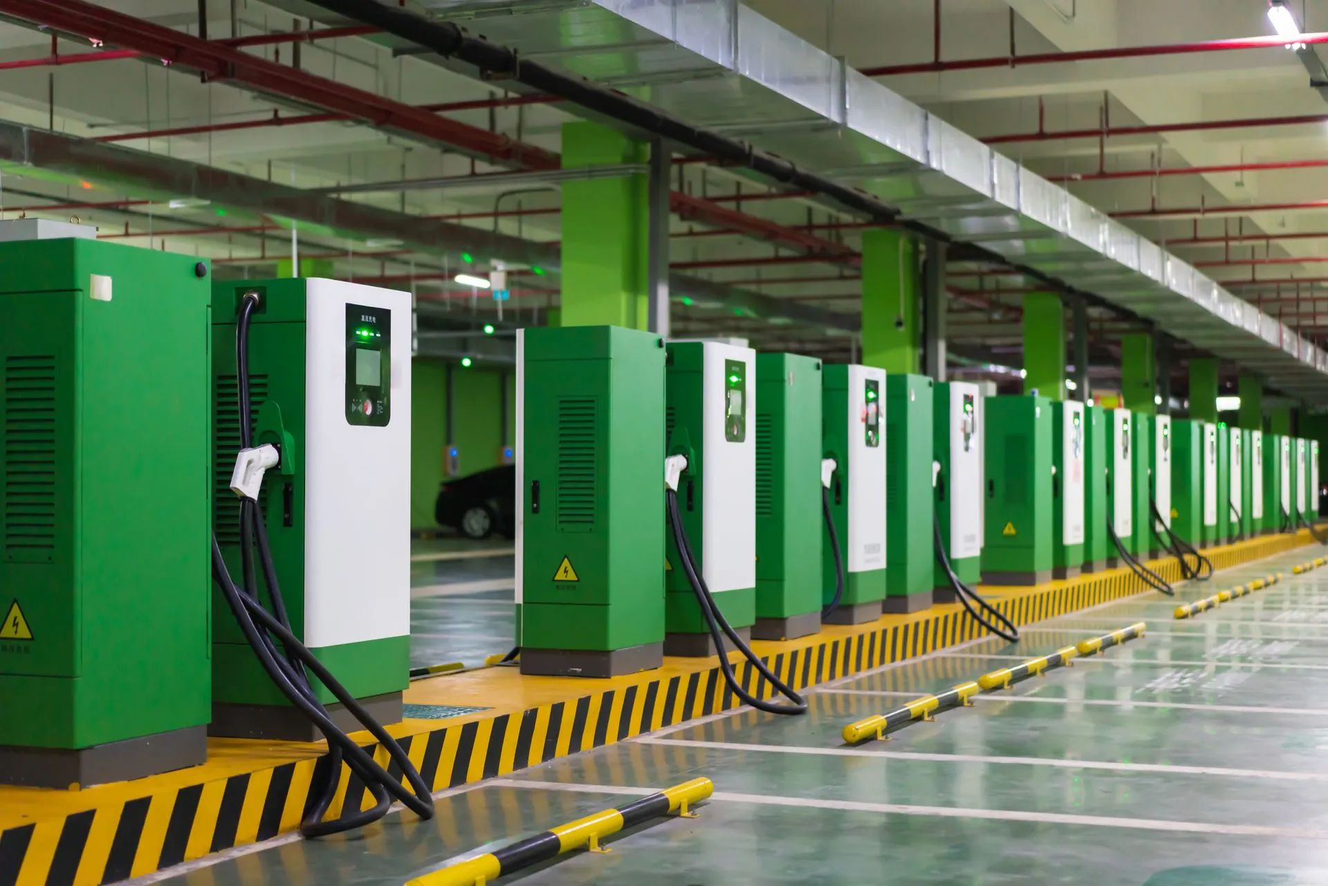 A row of green and white charging stations in a parking garage.