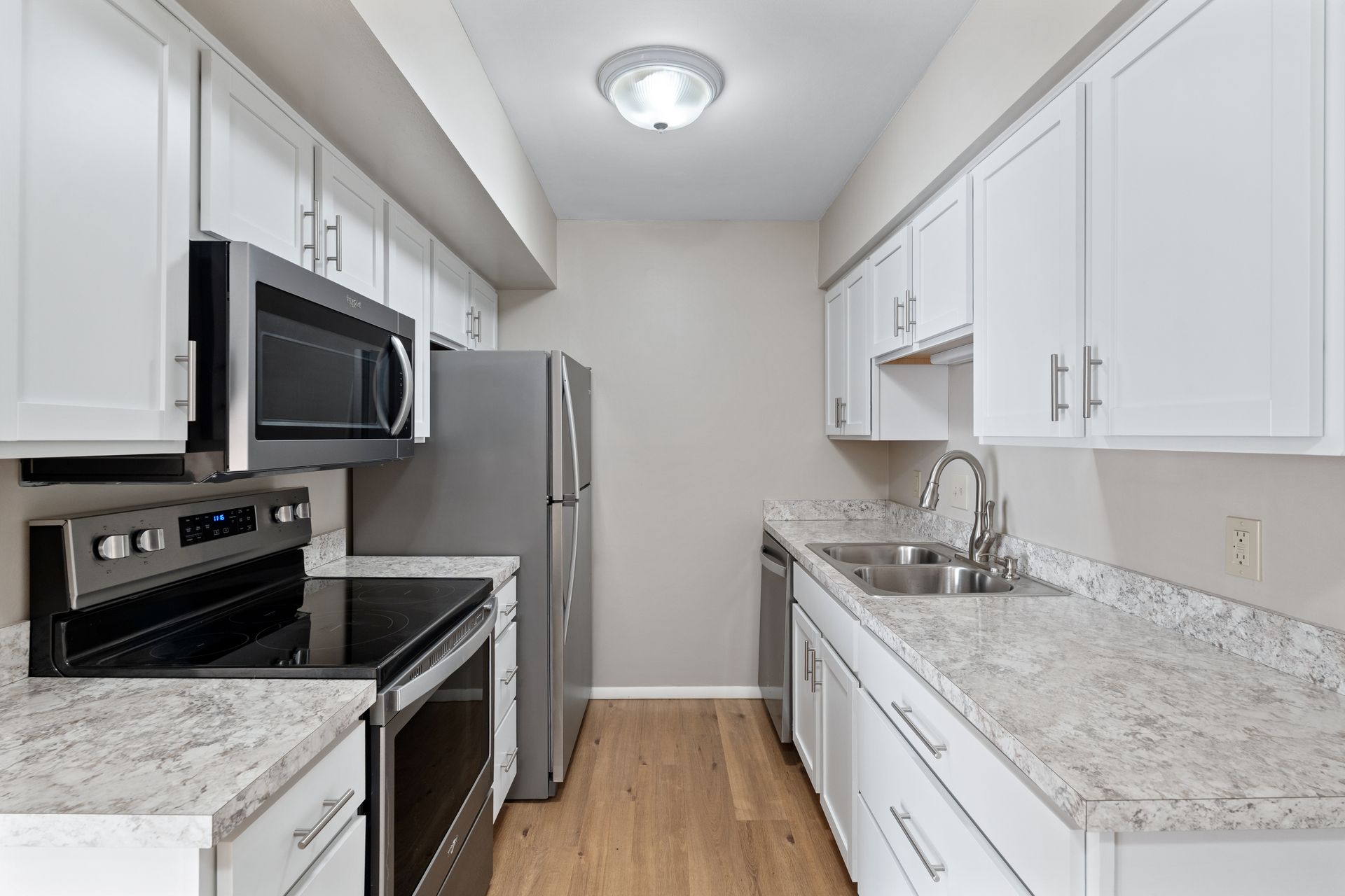Modern kitchen with white cabinets, stainless steel appliances, and light countertops.
