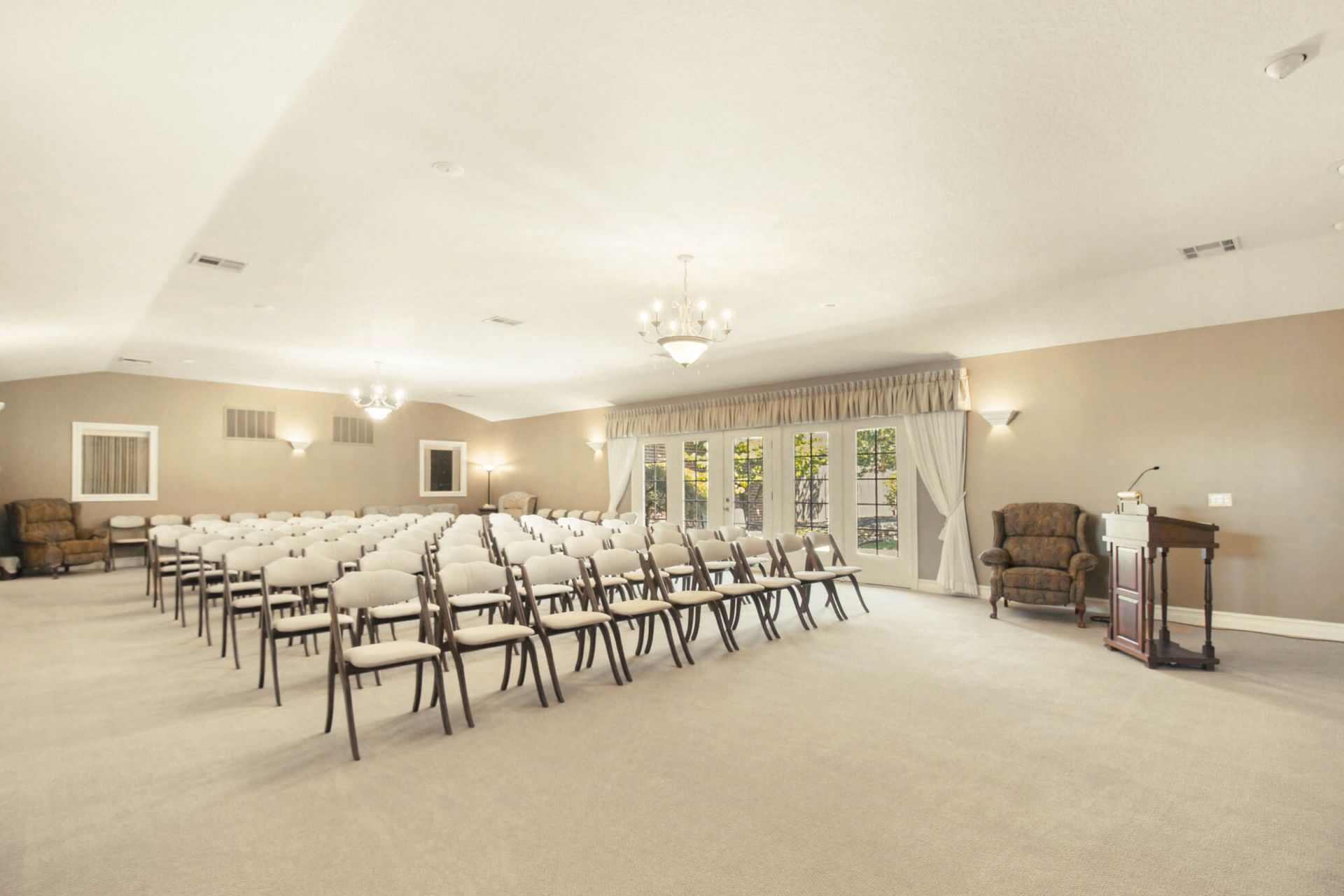 Empty event hall with rows of chairs facing a podium, neutral tones.