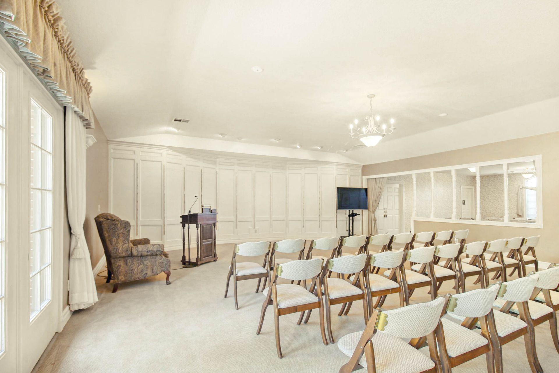 A light and airy chapel with rows of chairs, a podium, and a television.