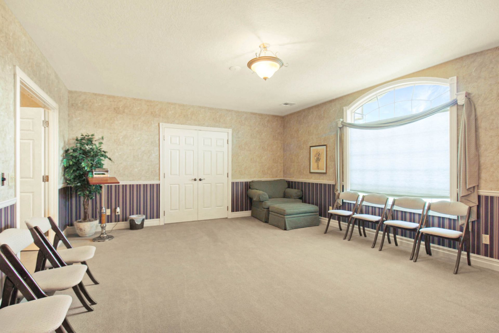 Funeral home interior with chairs, sofa, and window.