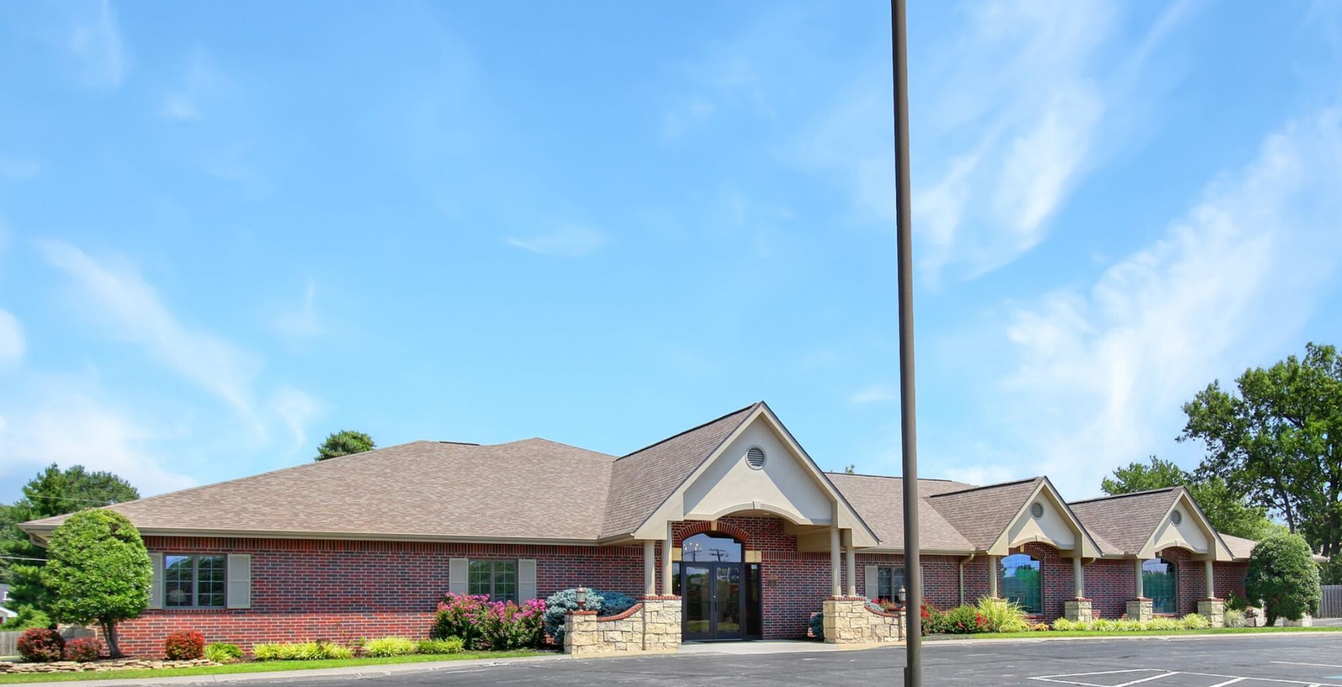 Brick building with brown roof, a light blue sky background.