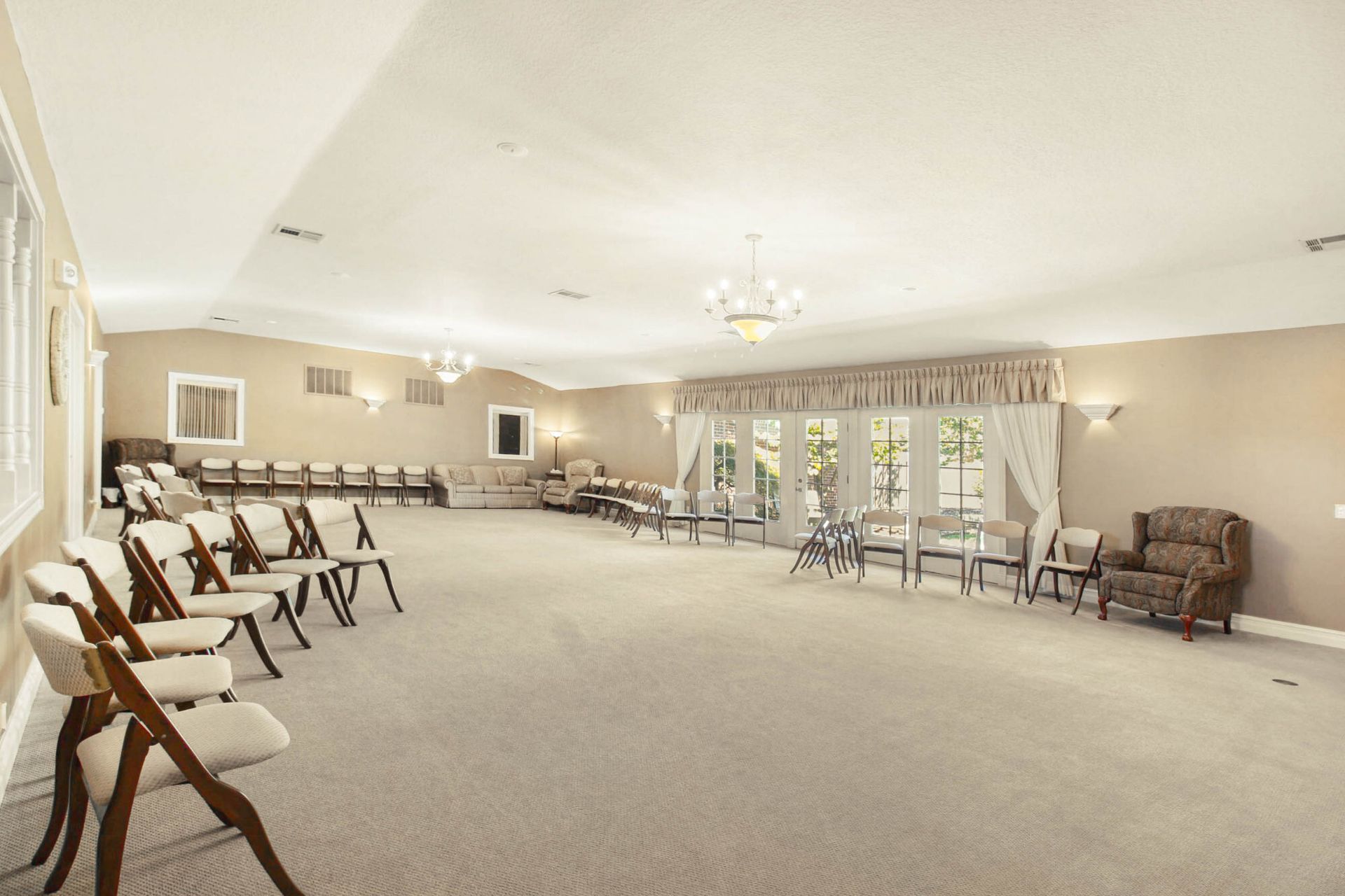 Empty beige room with rows of chairs; likely a funeral home or event space.