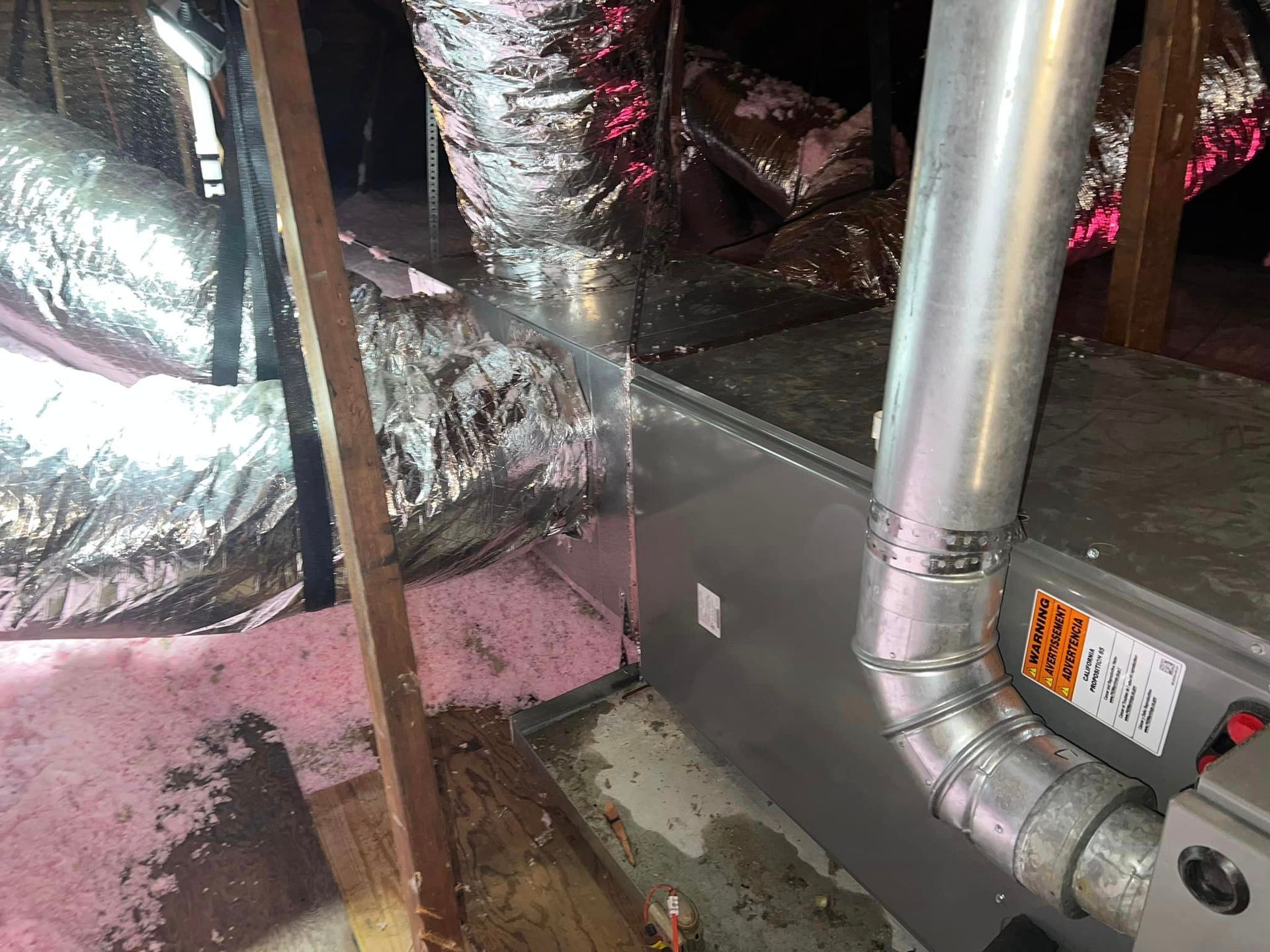 A close up of a ventilation system in an attic.