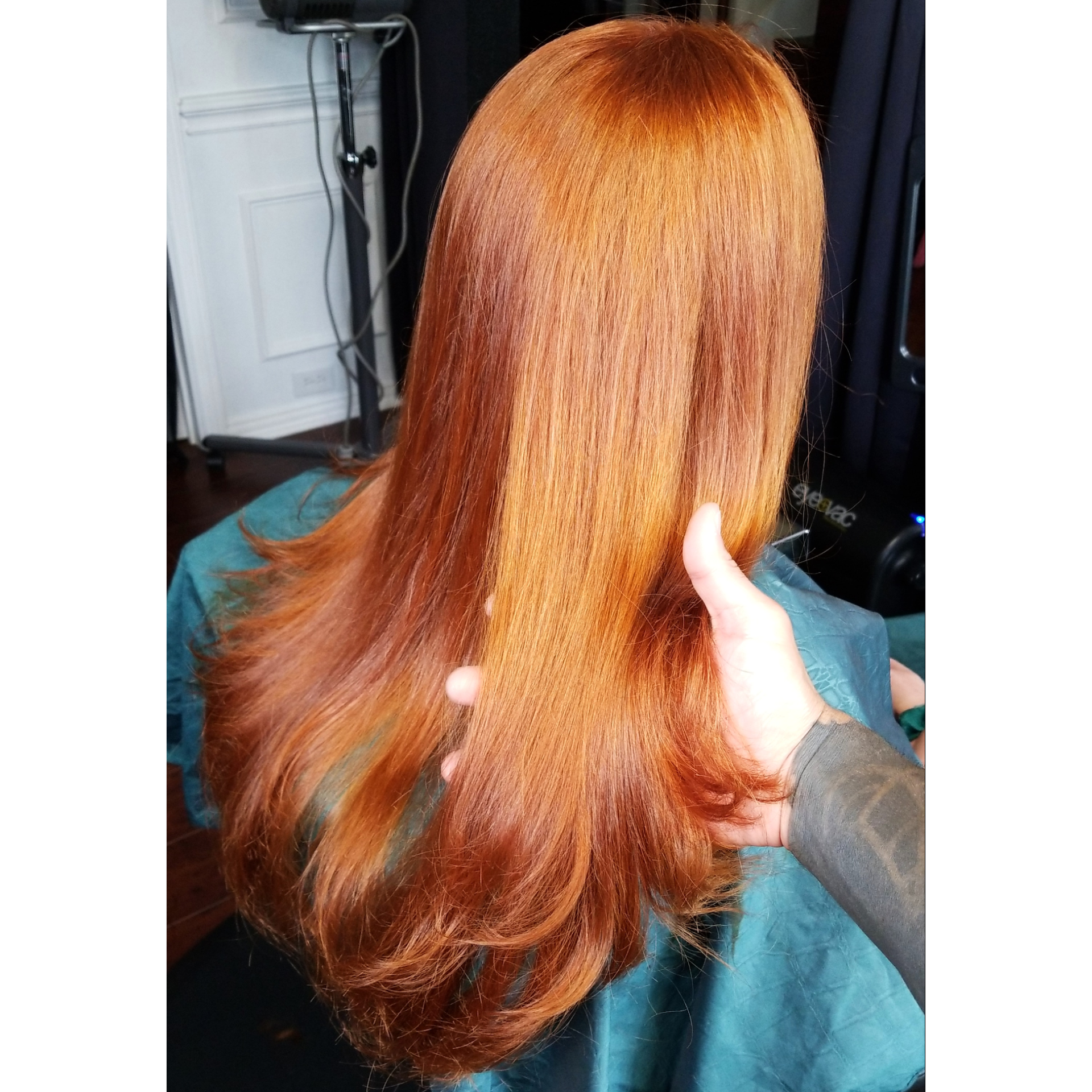 A woman with long red hair is getting her hair cut by a hairdresser.