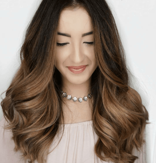 A woman with long brown hair is wearing a choker necklace.