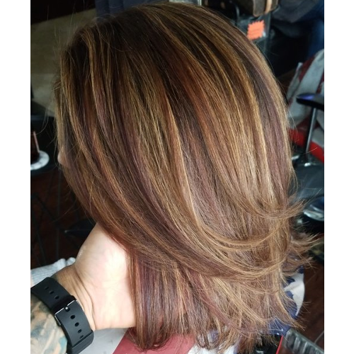 A woman with a watch on her wrist is holding her hair.