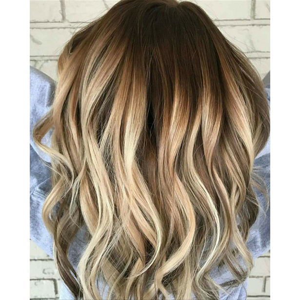 A woman with long wavy brown hair with blonde highlights