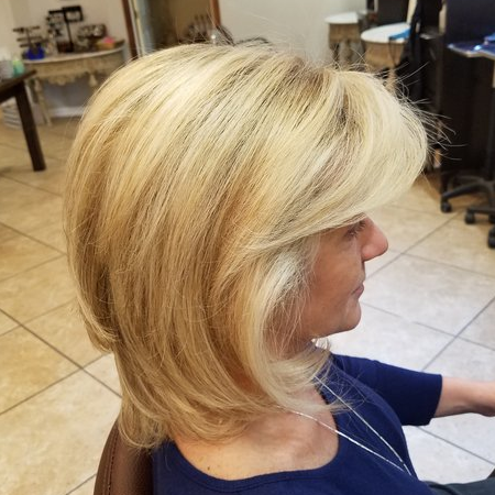 A woman with blonde hair is sitting in a chair.