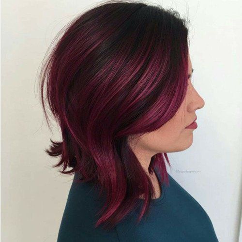 A woman with burgundy hair is wearing a blue shirt.