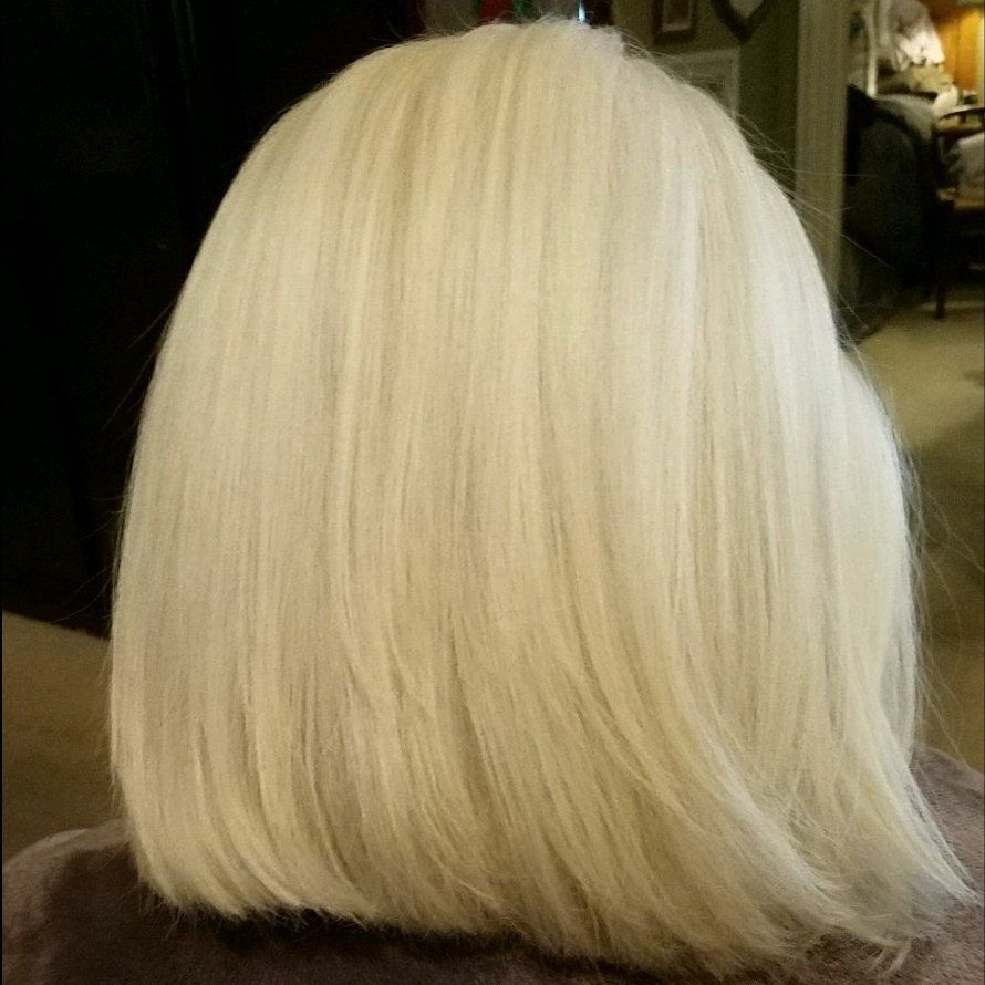 A woman with blonde hair is sitting on a chair in a room.