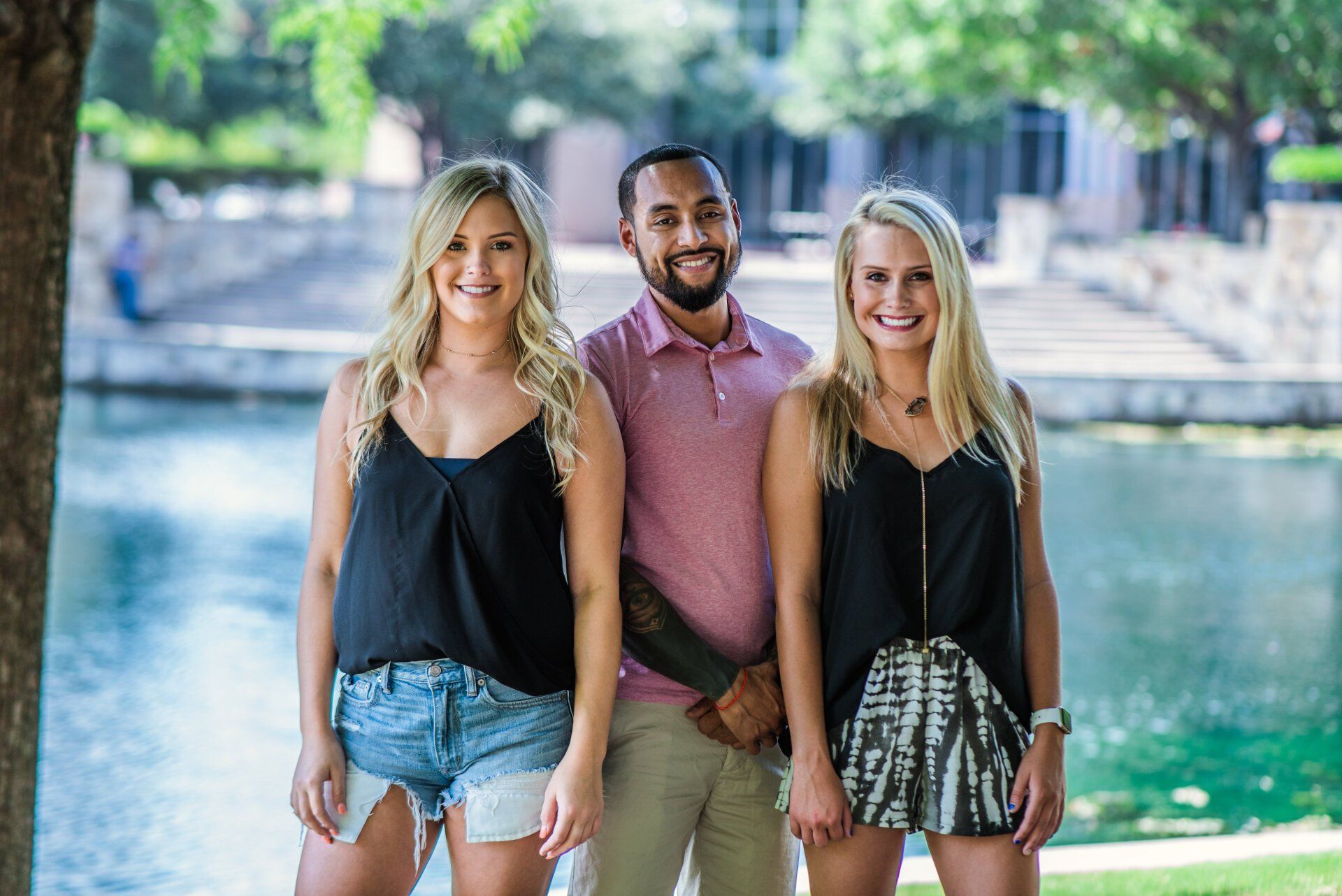 A man and two women are standing next to each other in front of a body of water.