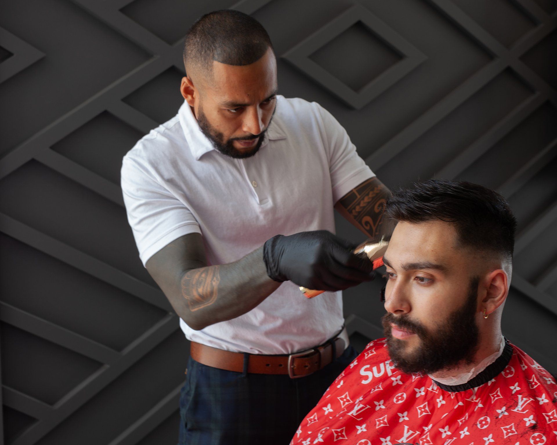 A man is getting his hair cut by a barber wearing a supreme shirt