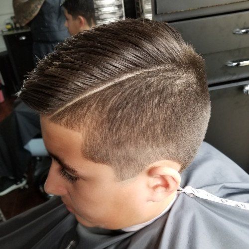 A young boy is getting his hair cut at a barber shop.
