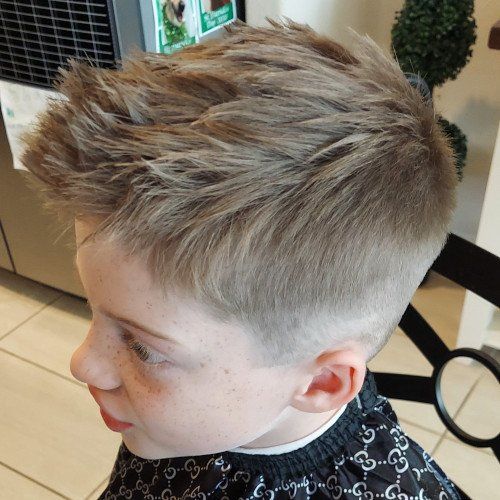 A young boy is getting his hair cut in a salon