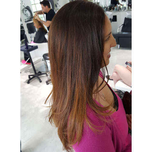 A woman in a pink shirt is getting her hair cut in a salon.