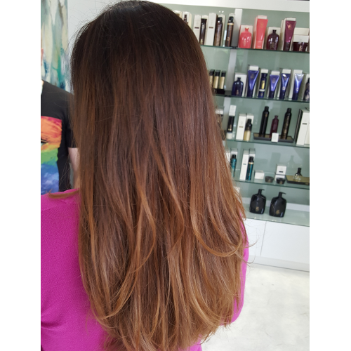 A woman with long brown hair is standing in front of a display of hair products.