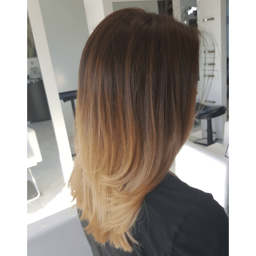 A woman with long hair is sitting in a chair in a salon.