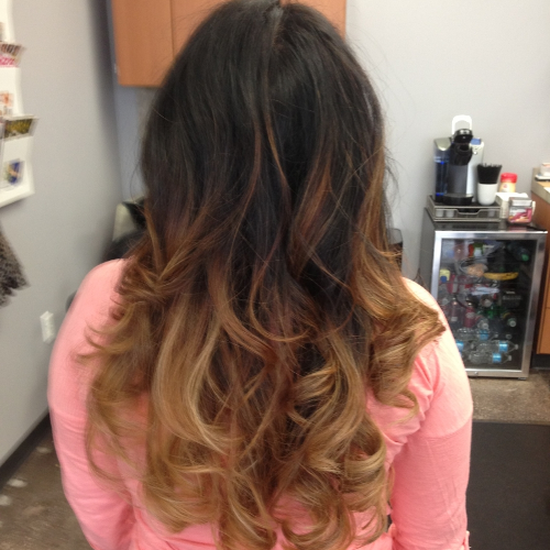 A woman with long dark hair is wearing a pink shirt