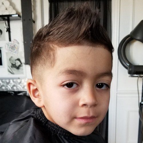 A young boy is getting his hair cut at a barber shop.