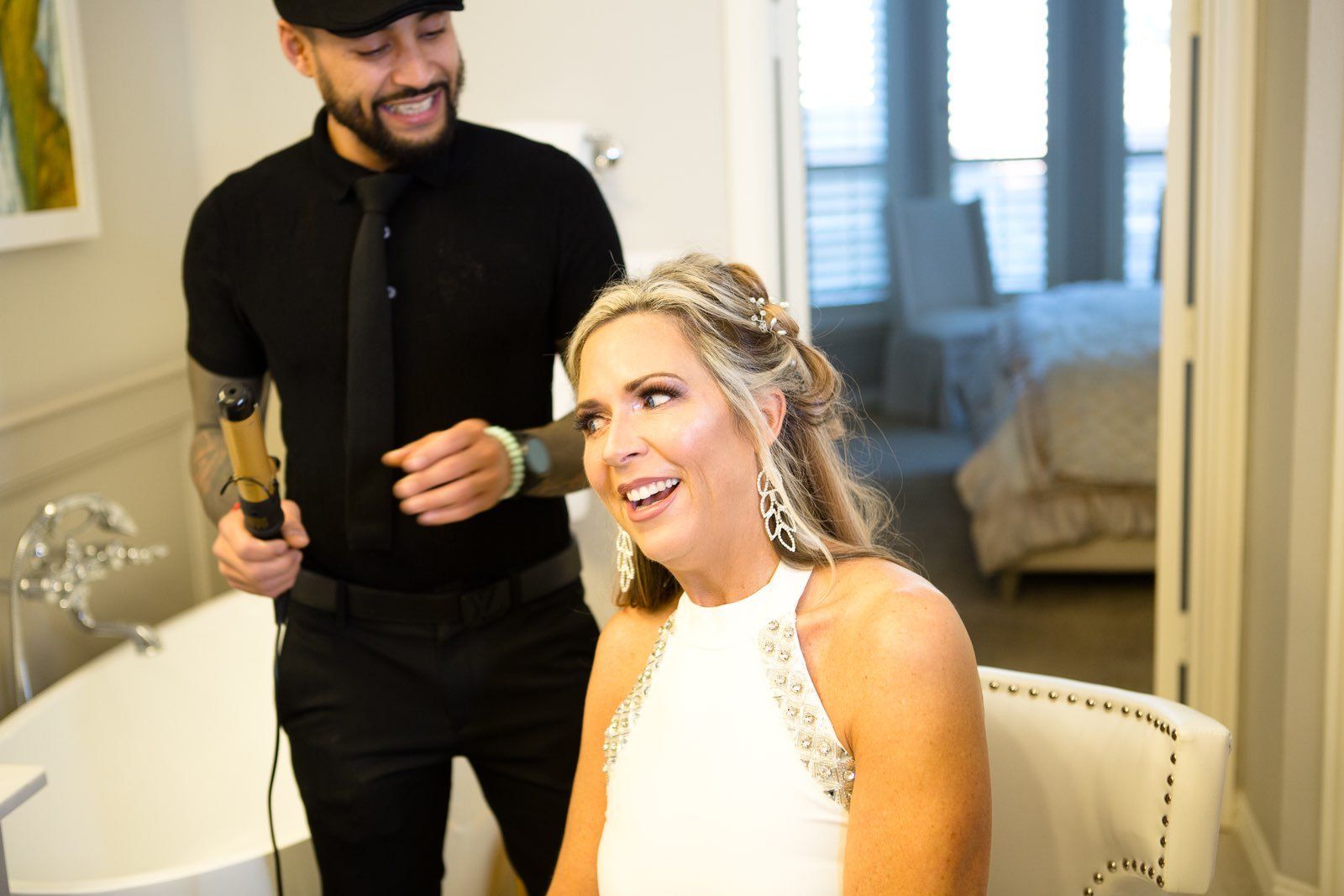 A man is blow drying a woman 's hair in a bathroom.